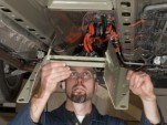 GM engineer fits structural reinforcement to distribute crash energy away from Chevy Volt battery.