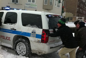 Rahm Emanuel helps push a police vehicle out of the snow